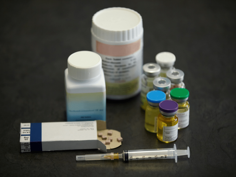 Steroid pills and liquids alongside a syringe